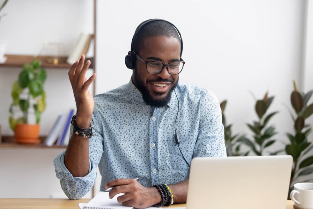 create a sharp and realistic image of an african american student doing trascription work on an apple laptop and headphone
